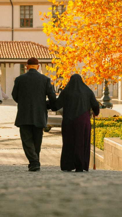 A senior couple walking together outdoors in a park setting