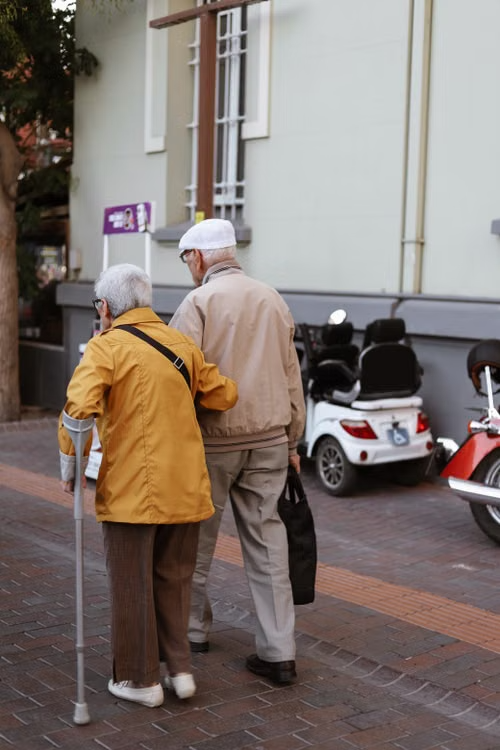A senior couple walking together outdoors with support