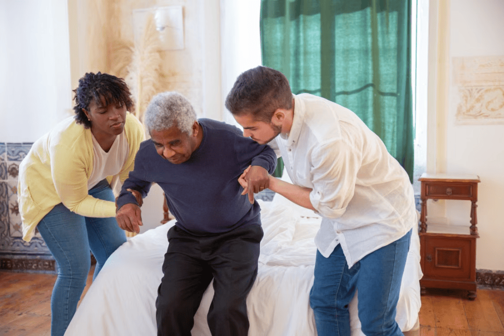 Two caregivers helping an elderly person stand