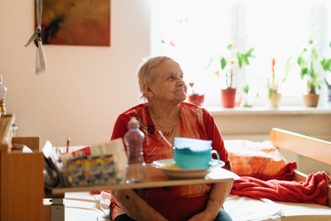 A person sitting on a bed with food in front of them on a table 
